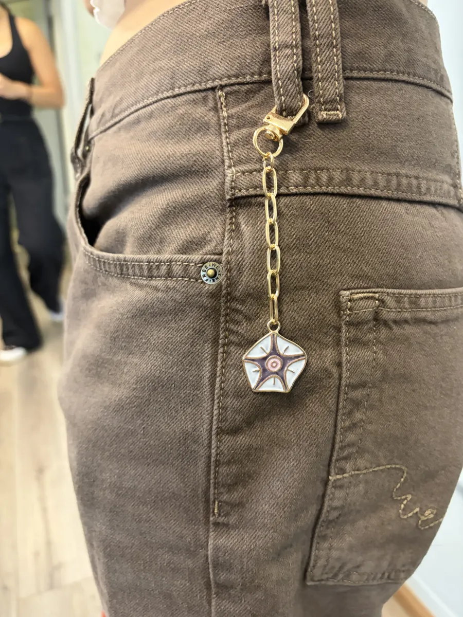 A finished enamel flower charm clipped to jeans